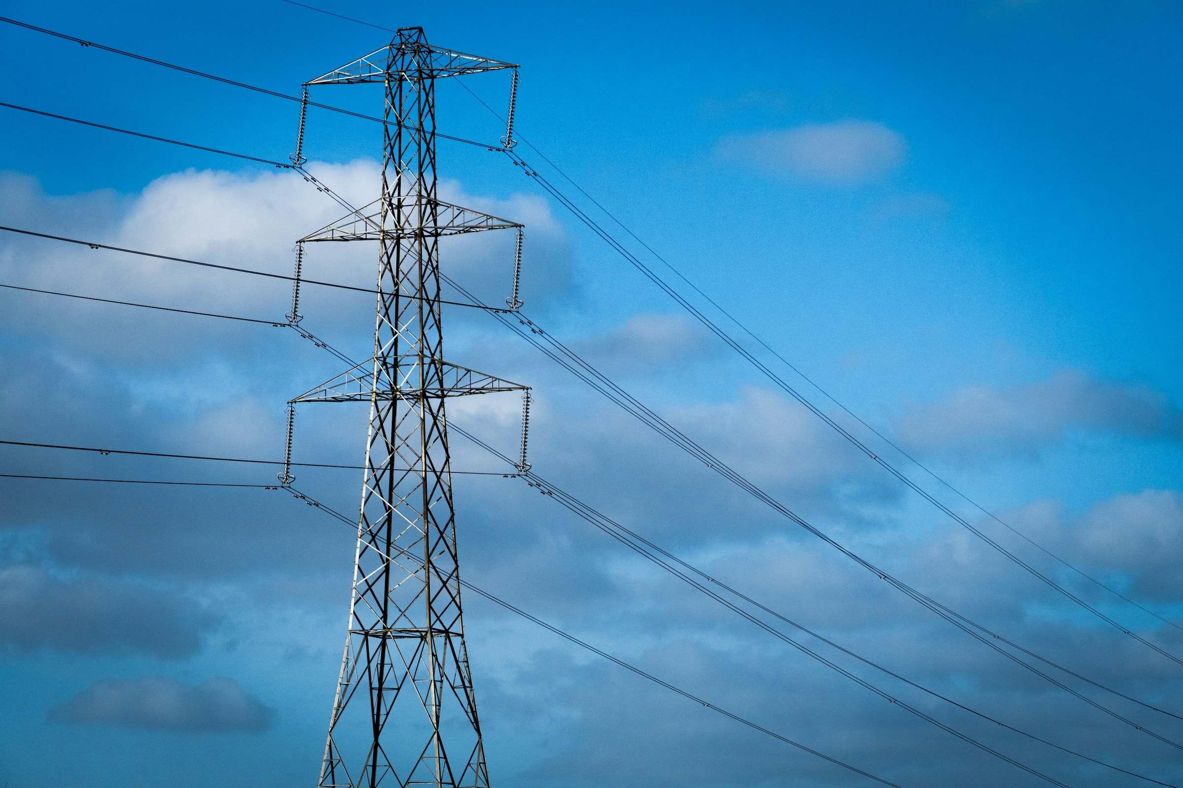 Hochspannungsmast vor blauem Himmel, Inkasso für Energieversorger